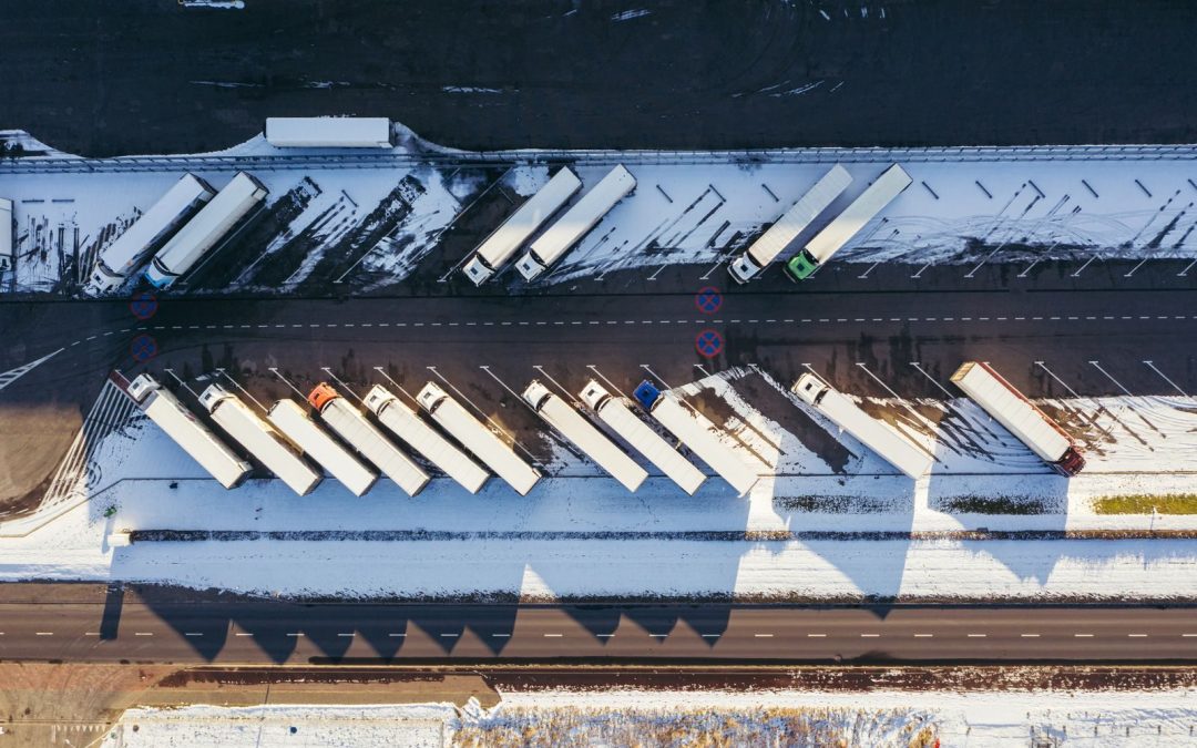 Top-down aerial view of trucks parked in a snowy lot in Poznań, Poland, showcasing winter logistics.