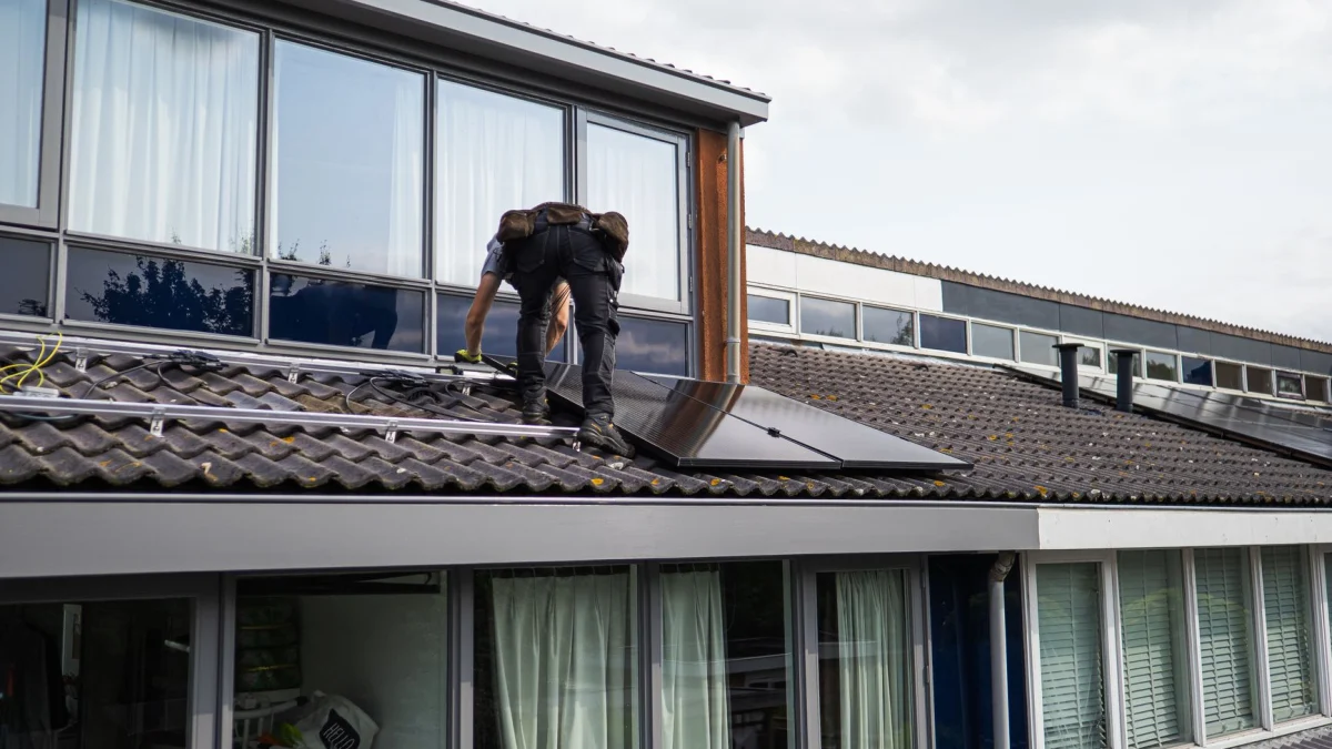 Technicus is bezig met het installeren van zonnepanelen op een residentieel dak tijdens de dag.